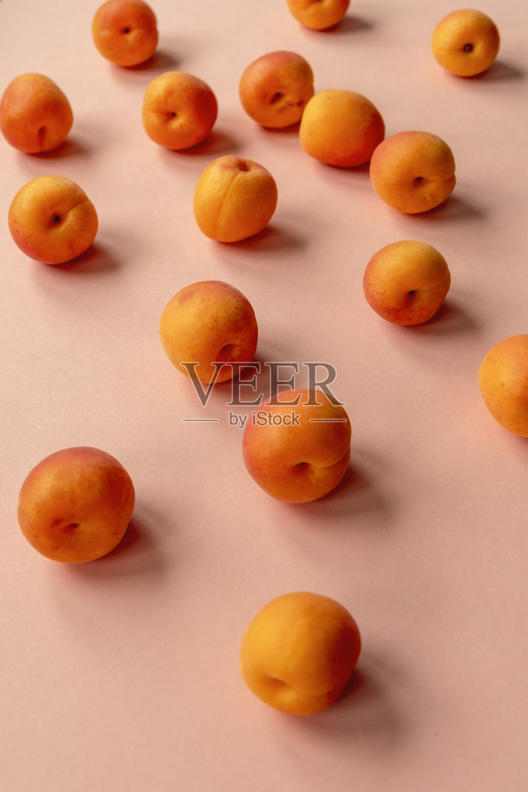 橙色的杏子散落在粉红色的桌子上照片摄影图片