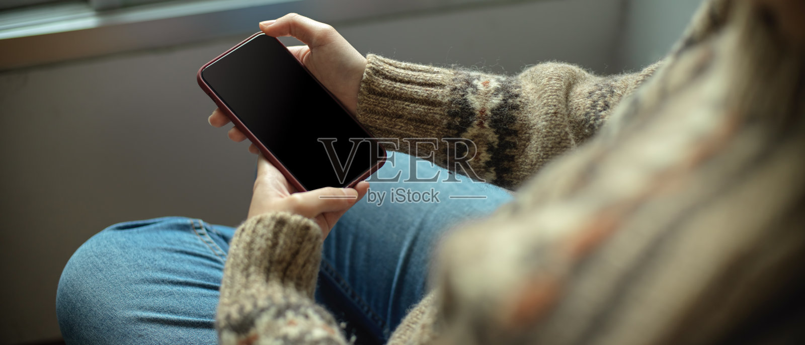 年轻的女大学生放松地躺在窗边的椅子上使用智能手机照片摄影图片