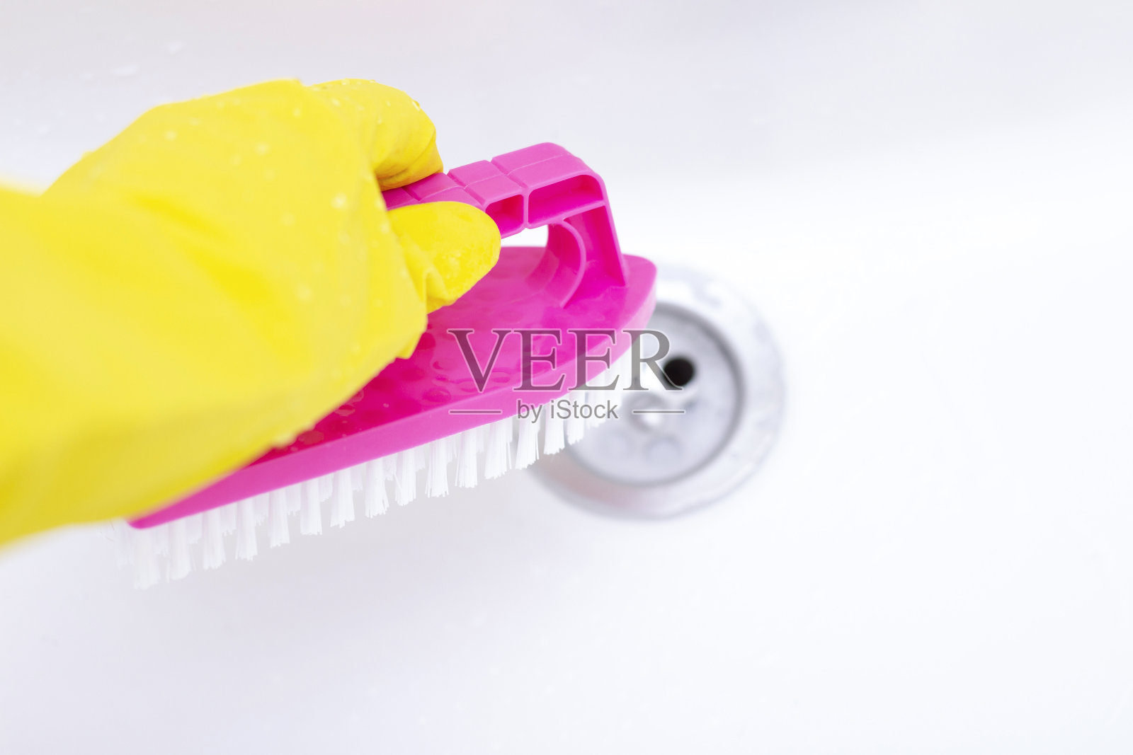 戴着黄色橡胶手套的男子在清洗浴室的水槽。在水槽上做家务照片摄影图片