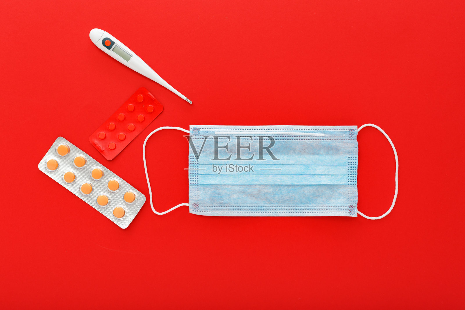 Covid-19医用口罩，医用防护口罩，红色背景的药丸注射器温度计。冠状病毒的健康保险。医疗保健和医疗理念。照片摄影图片