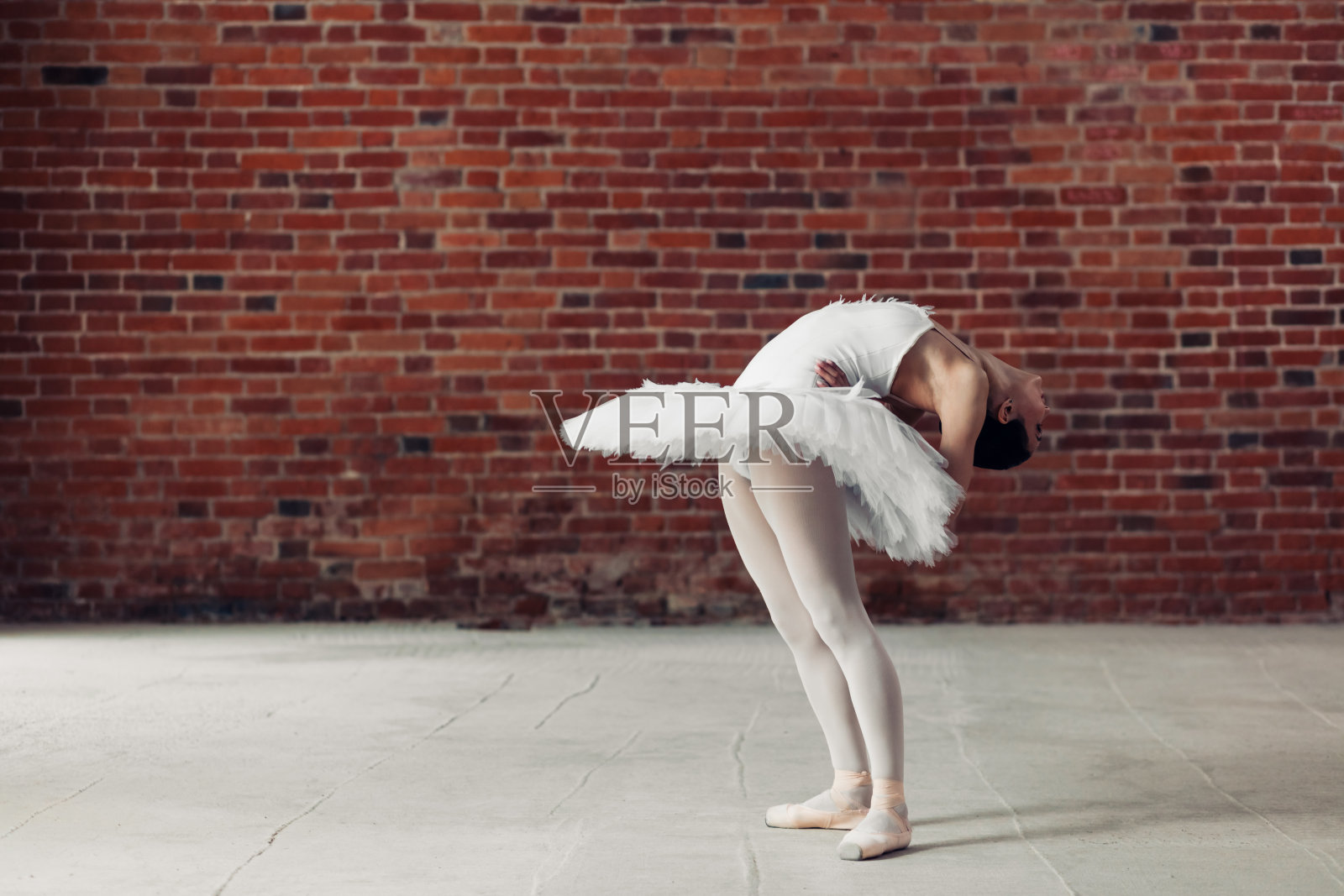 优雅的芭蕾舞演员弯着背。在舞蹈工作室拍摄。照片摄影图片