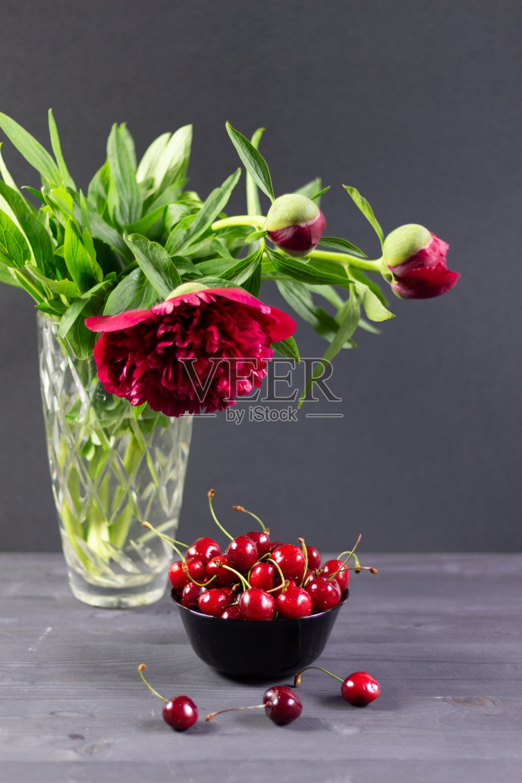 红色成熟樱桃碗和农家乐花束花瓶在黑色木制背景照片摄影图片