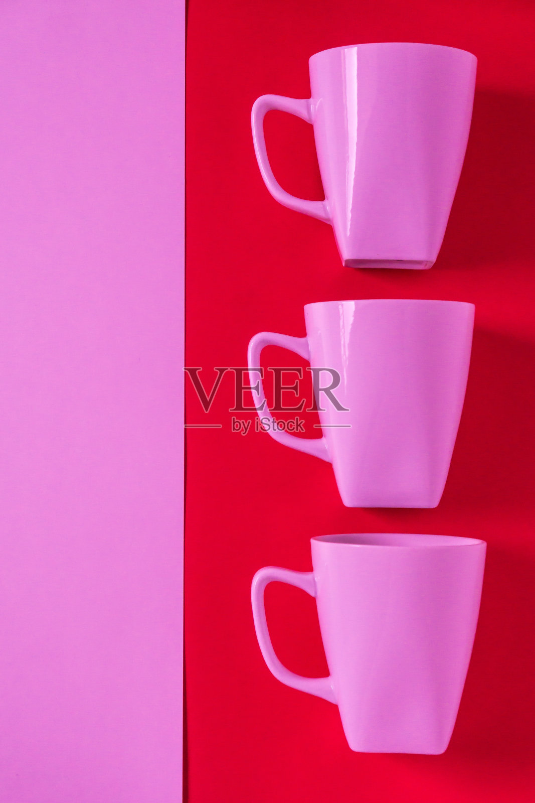 3个粉色的冬季咖啡杯，马克杯排成一排，用于休息时间开会;带有红色垂直背景上用于复制文本的空白空间的拷贝空间;女性情人节主题。照片摄影图片