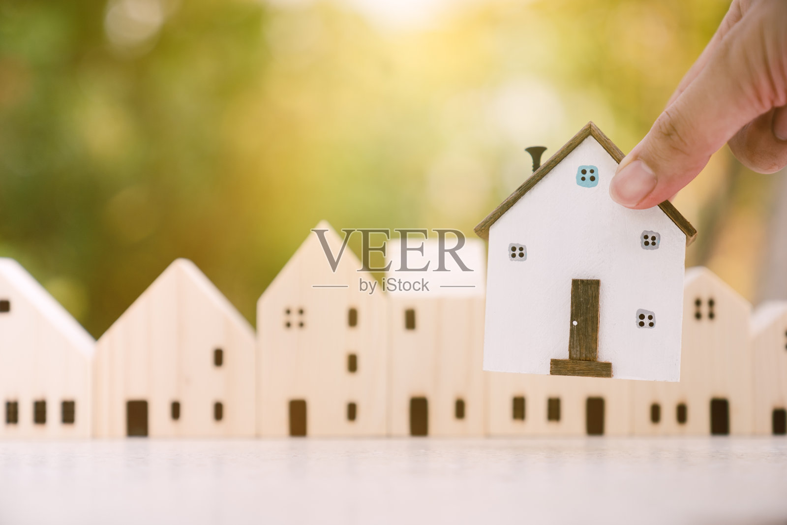 手选迷你木屋的模型，从模型和木桌上的钱币排列，选择性的重点，计划购买房产。选择最好的。象征着建筑、生态、贷款的概念照片摄影图片