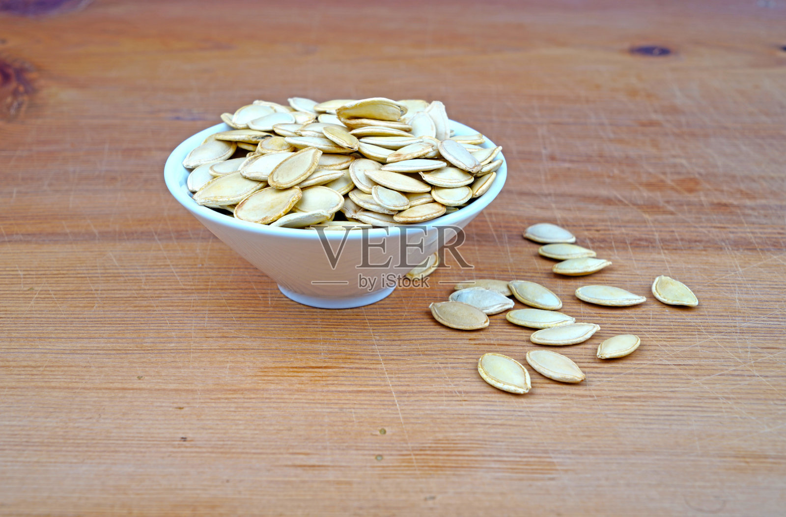 一盘有机南瓜籽和洒在木制背景上的南瓜籽照片摄影图片