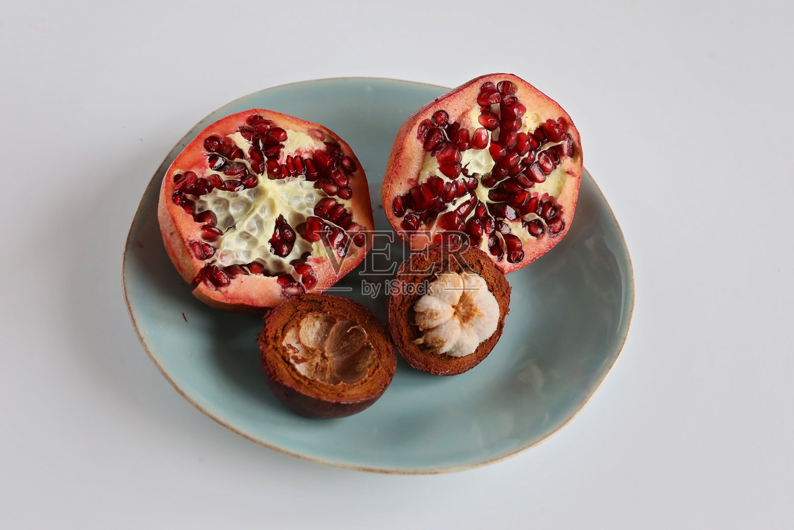 把紫色山竹和石榴切成片放在盘子里照片摄影图片