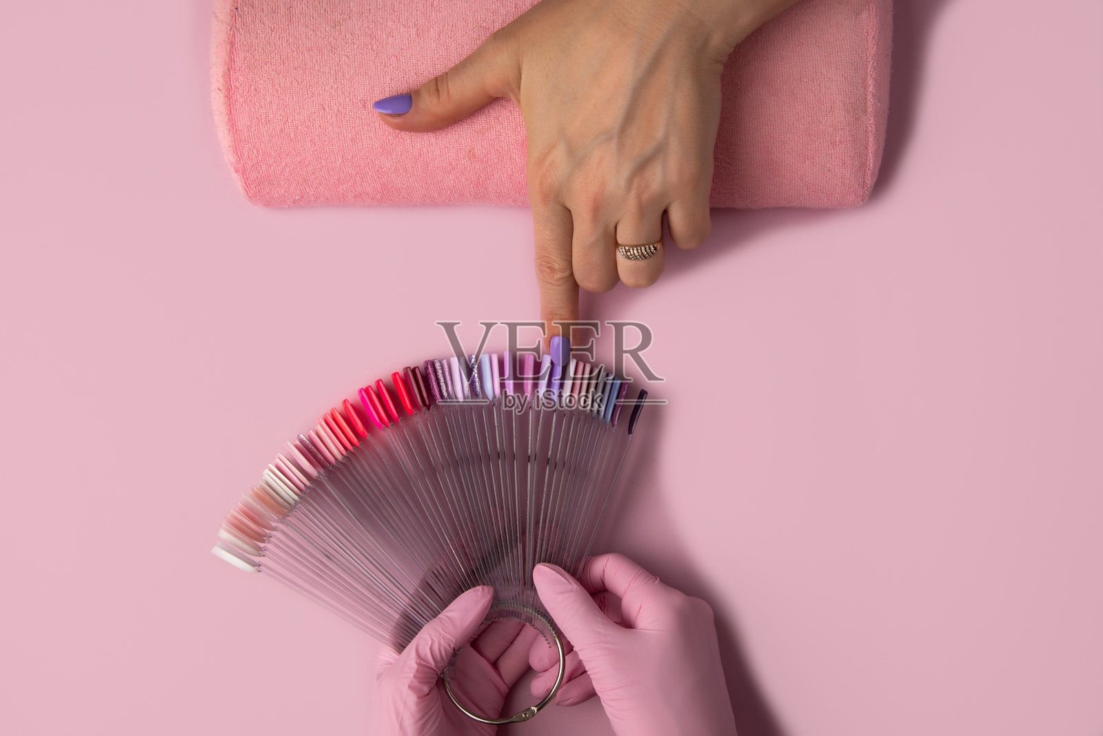 在粉红色背景上修甲过程，俯视图。在美容院修指甲。修指甲的概念,照片摄影图片