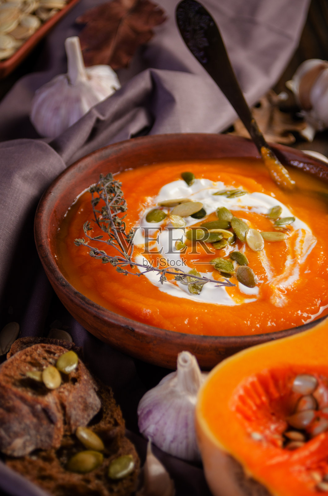 泥菜，自制的乡村南瓜汤和种子放在木桌上，面包和蔬菜放在一边照片摄影图片