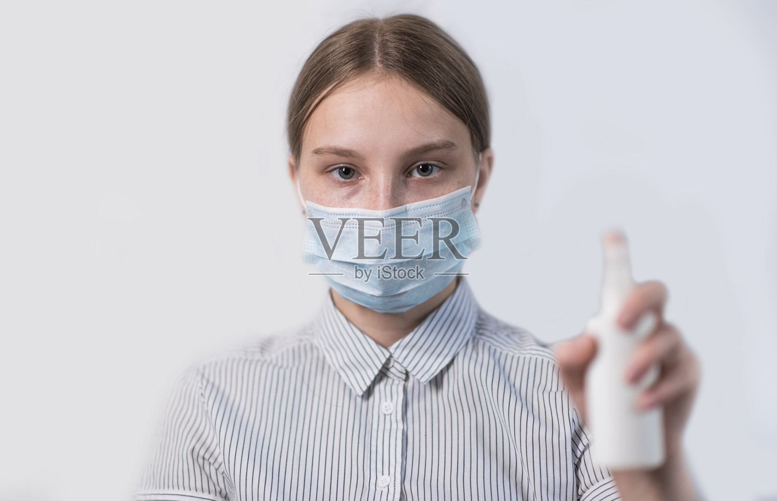 戴口罩的少女使用消毒喷雾，注意眼部，预防病毒感染，注意流感，居家隔离，阻止新冠疫情照片摄影图片