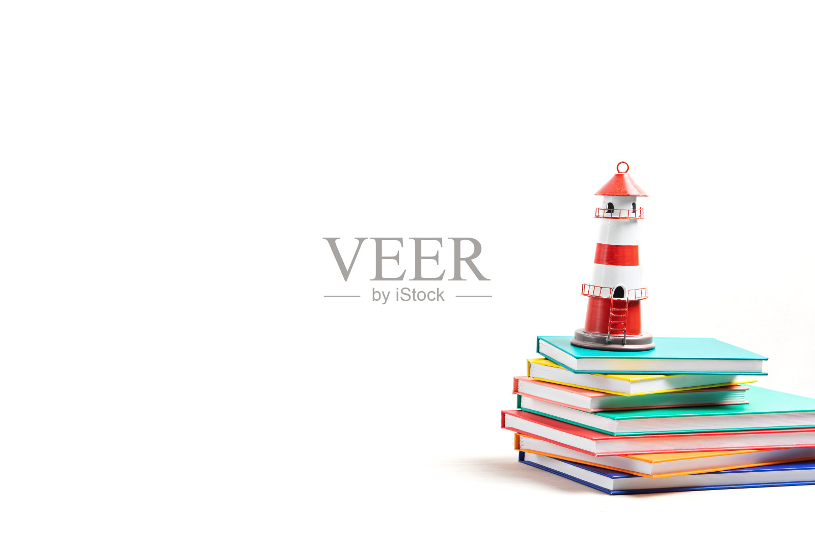 灯塔屹立在那堆书上。国际扫盲日，书籍冒险，想象和旅行照片摄影图片