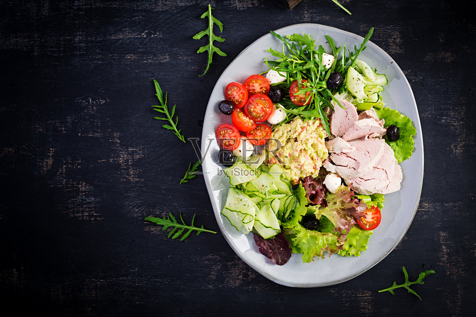 生酮饮食。晚餐配水煮猪肉，鳄梨鳄梨色拉酱，西红柿，黄瓜，马苏里拉奶酪，黑橄榄和芝麻菜。排毒和健康理念。酮类的食物。开销,俯视图照片摄影图片