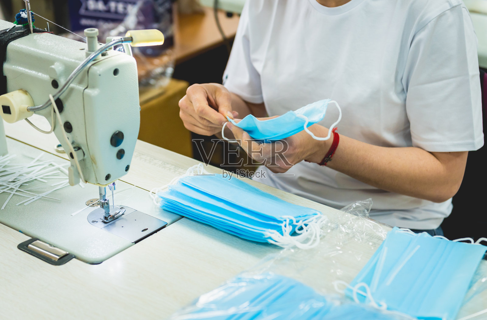 女人在缝纫机上缝面部医疗。冠状病毒大流行病。照片摄影图片