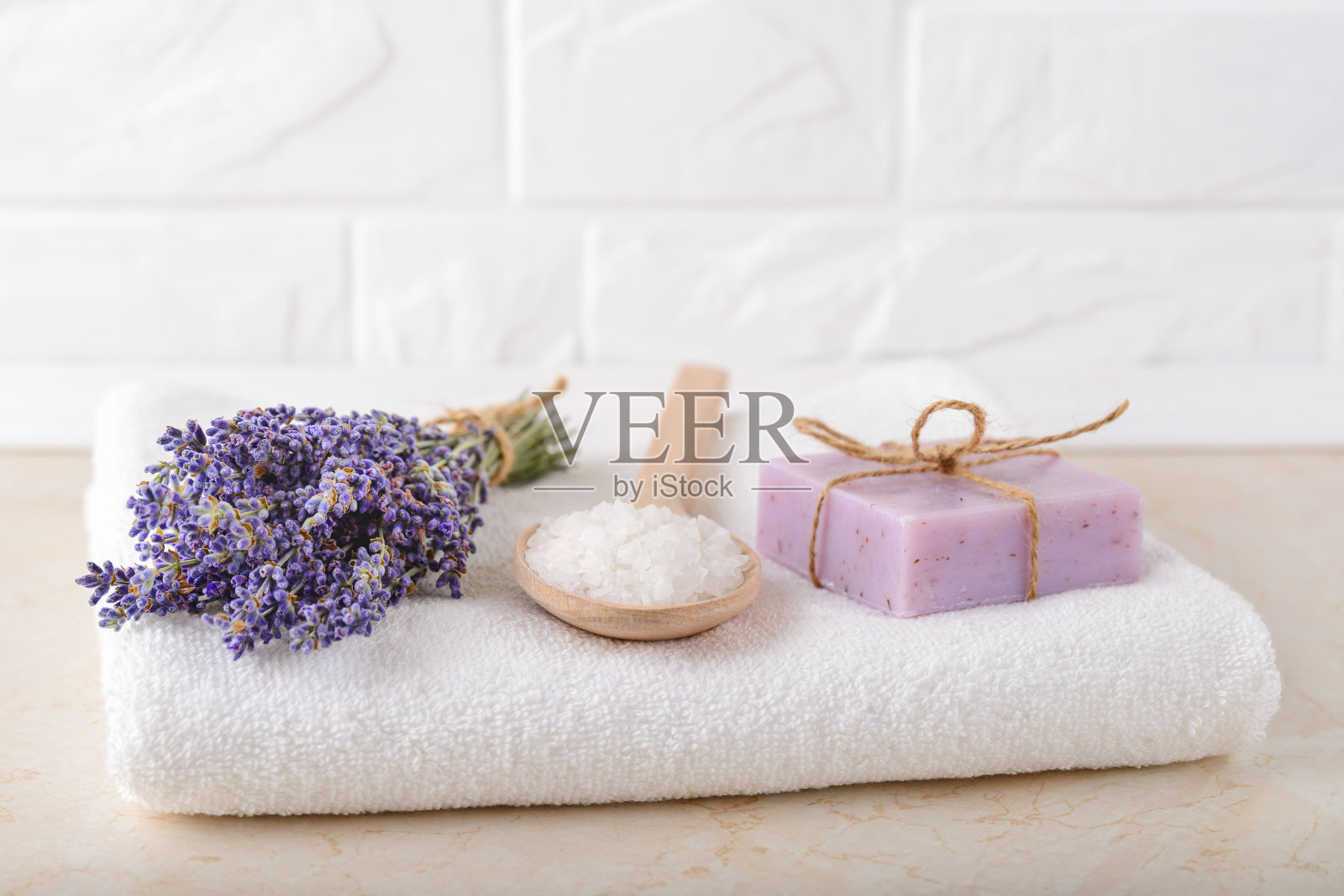 新鲜芳香的薰衣草，木质汤匙里的化妆浴盐，浴室里白色毛巾上的薰衣草肥皂。自制水疗、护肤、美容的概念。照片摄影图片