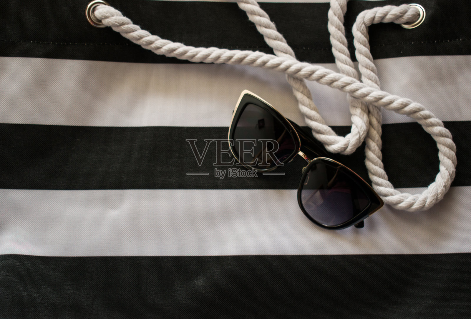 女人的太阳镜在白色和黑色的沙滩包照片摄影图片