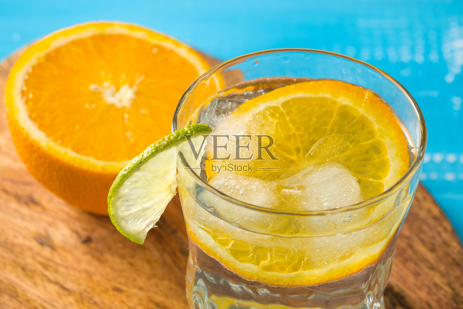冷的夏季美味的鸡尾酒与酸橙和冰在玻璃与滴在白色和蓝色的背景。照片摄影图片