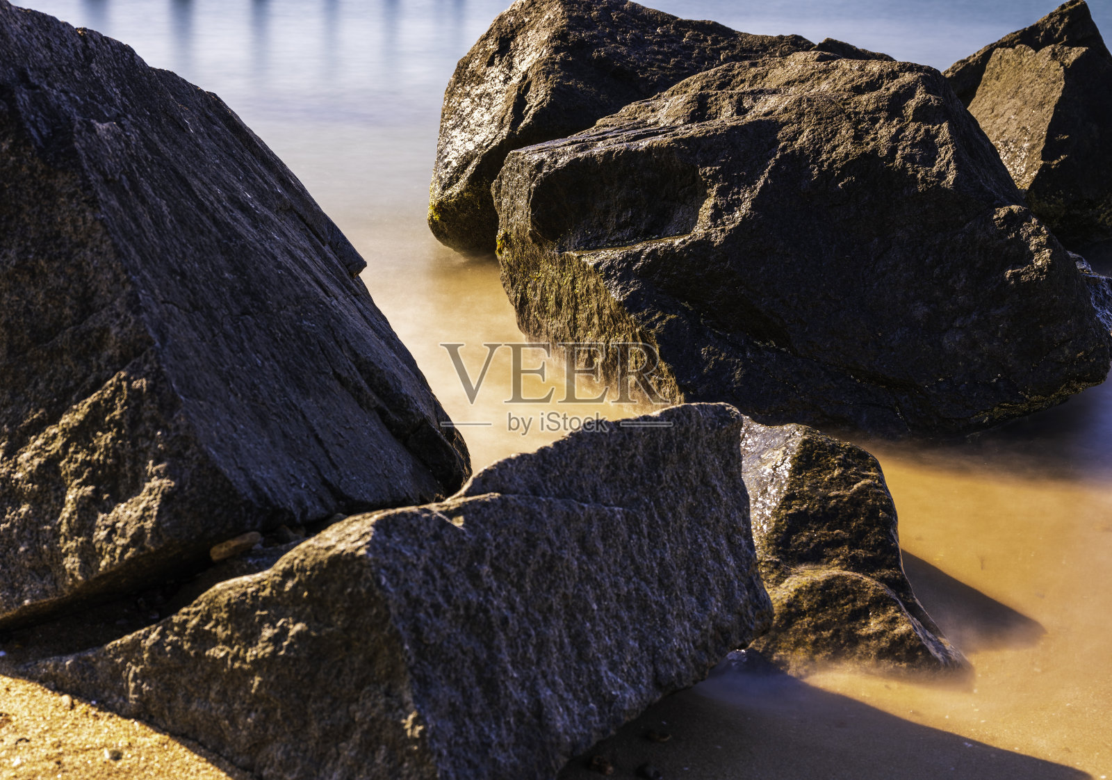 科德角海滩上质朴的黑色巨石，长曝光照片照片摄影图片