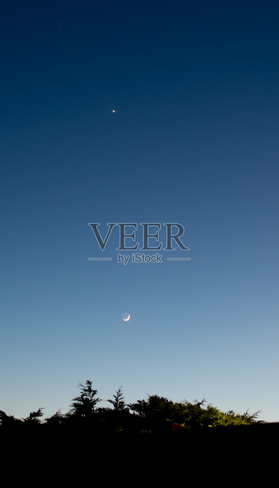 黄昏时分，金星悬挂在新月的上方照片摄影图片