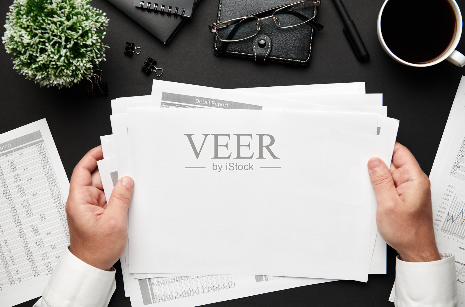 俯视图的商人的手工作与财务报告。现代黑色办公桌上有笔记本电脑，笔记本，铅笔和很多东西。平铺表布局。照片摄影图片