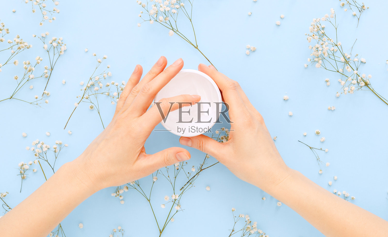 手霜，女性的手用有机的天然霜化妆品在一个柔和的蓝色背景。皮肤护理霜的罐子，为手，身体。平铺保湿霜，令肌肤柔软、健康、美丽。照片摄影图片