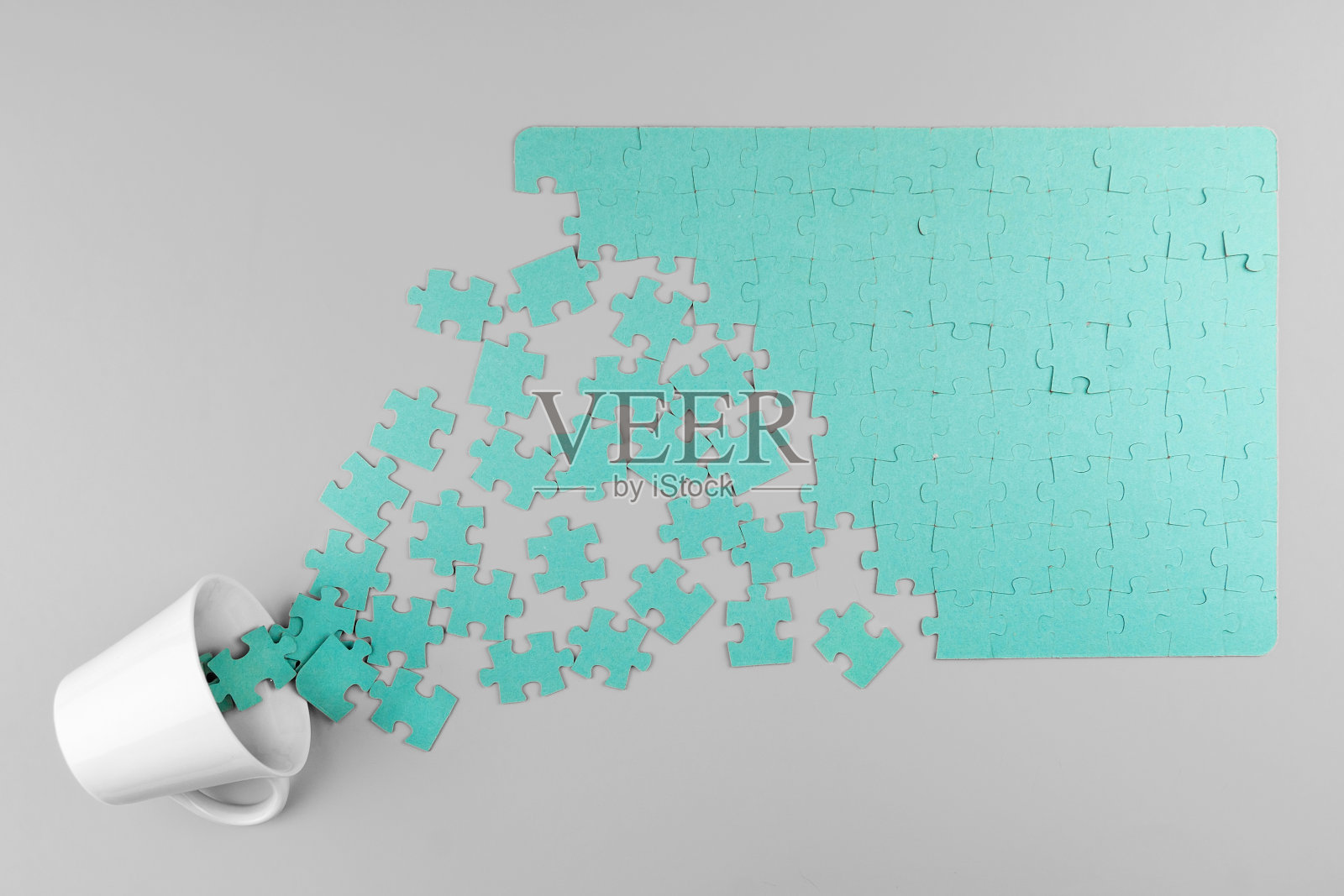 一个蓝色的拼图从咖啡杯里溢出来。照片摄影图片