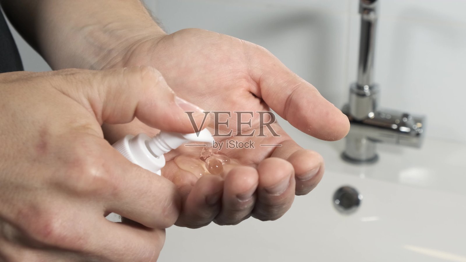 一个男人在浴室里把肥皂或药膏挤到手上。照片摄影图片