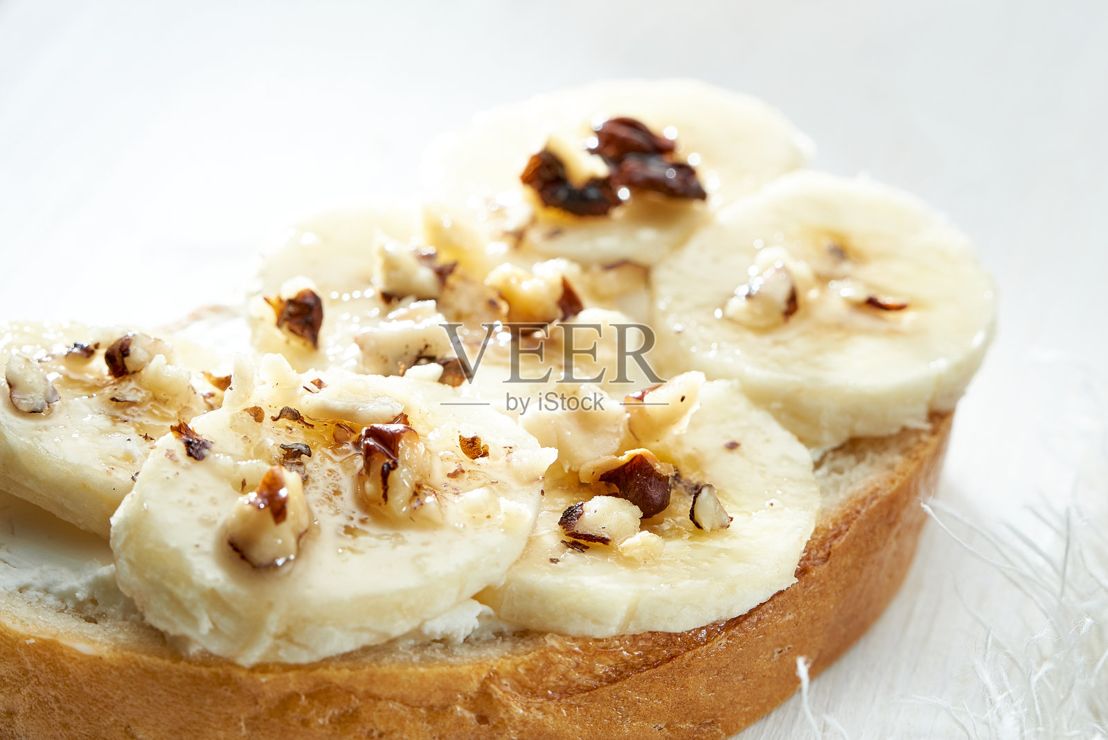 白色木桌上的三明治配香蕉片和坚果。照片摄影图片