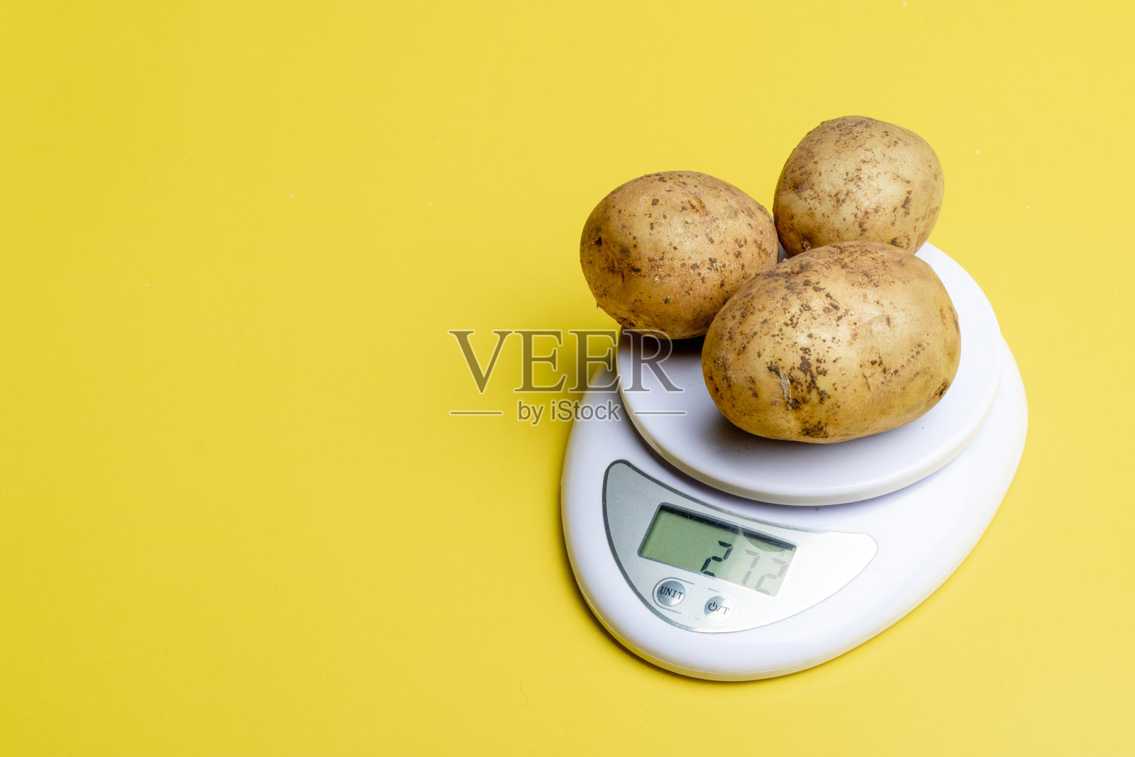 磅秤上称了三个土豆照片摄影图片