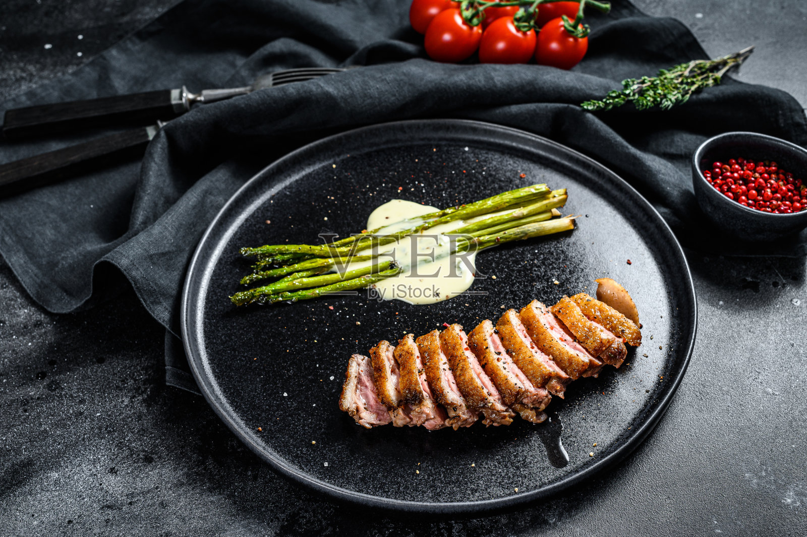 烤鸭柳配芦笋，香草和香料。黑色背景。前视图。照片摄影图片