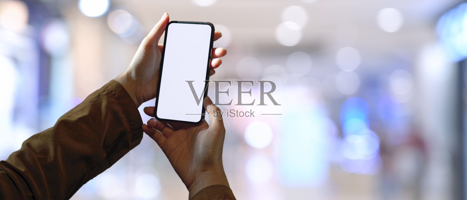 一名女子手持白屏智能手机，背景为散景照片摄影图片