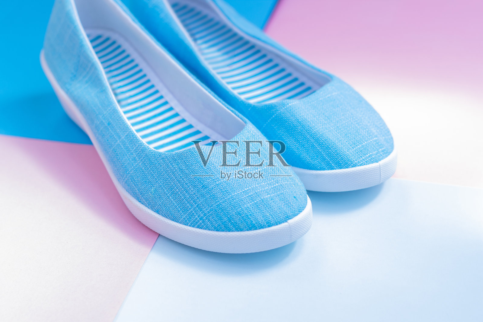 粉色和蓝色背景的休闲夏季鞋。女性或青少年时尚，蓝色拖鞋。都市鞋:平底鞋，便鞋，运动鞋。平放，俯视图，文本复制空间。购物和销售概念。照片摄影图片