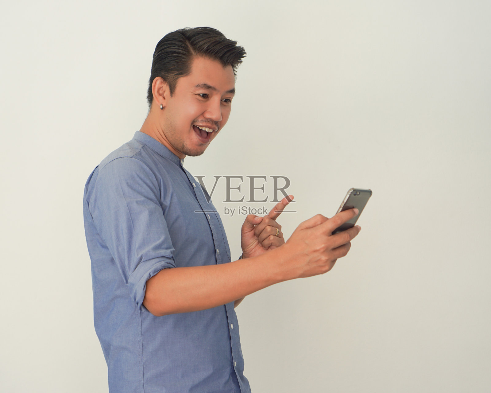 男人站在那里看着智能手机感觉很开心，微笑着，得到了主意照片摄影图片