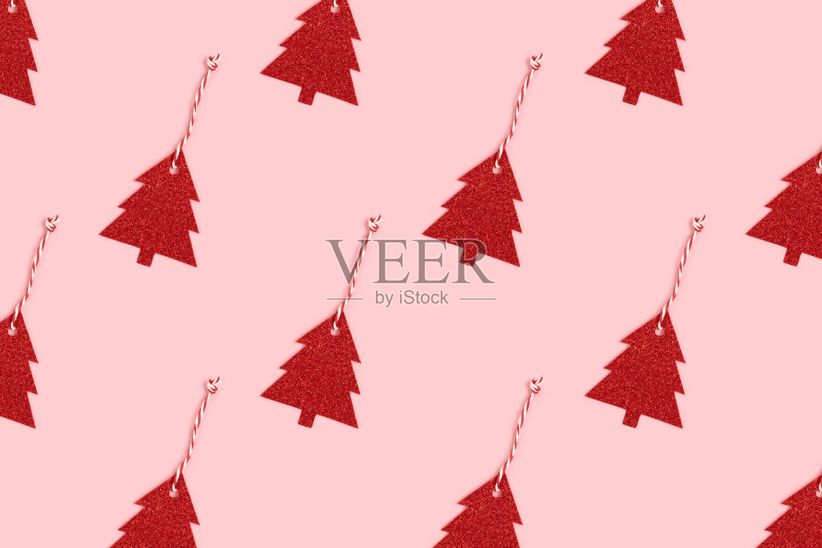 图案由红色的闪闪发光的新年装饰品在一个冷杉树的形状在粉红色的柔和的背景。照片摄影图片