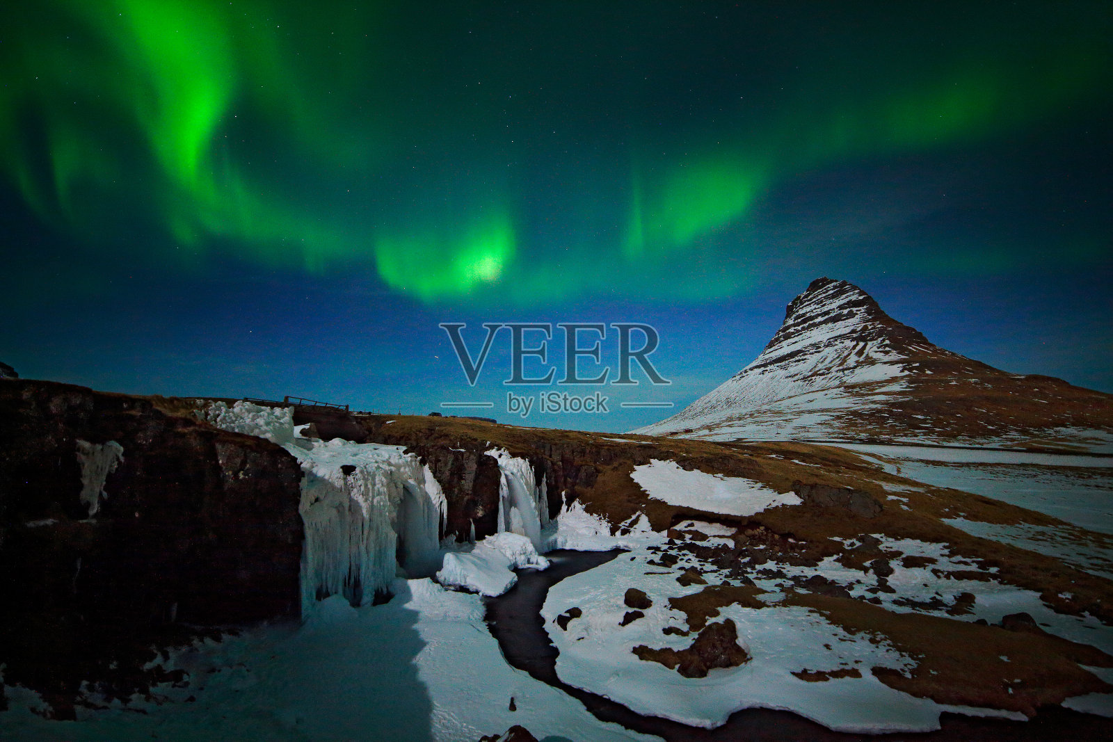 冰岛的北极光。冰岛Kirkjufell，美丽的绿色北极光在深蓝色的夜空和雪峰上。照片摄影图片