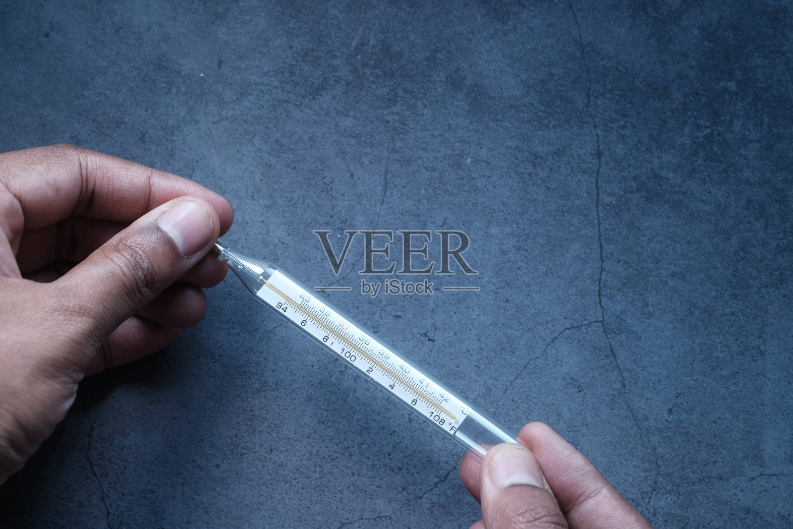 男子手持医疗温度计在灰色背景照片摄影图片