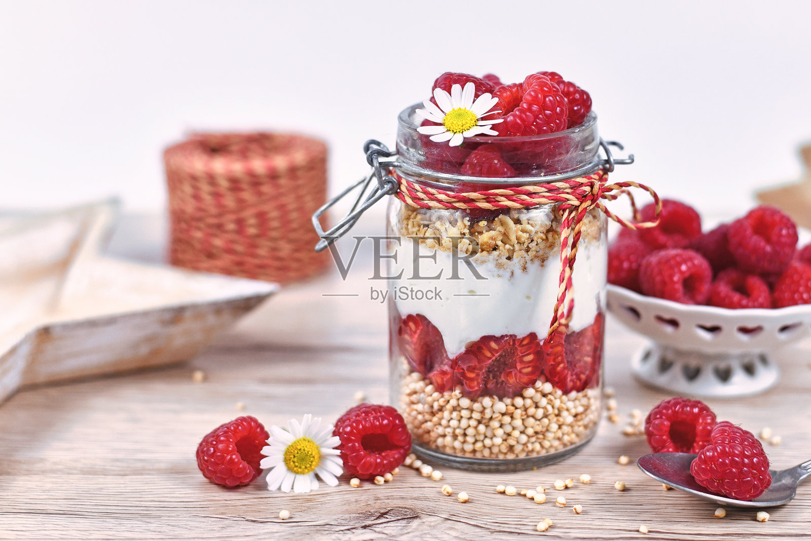 覆盆子水果甜点与skyr酸奶，格兰诺拉麦片和膨化藜麦谷物分层在坛子周围的配料照片摄影图片