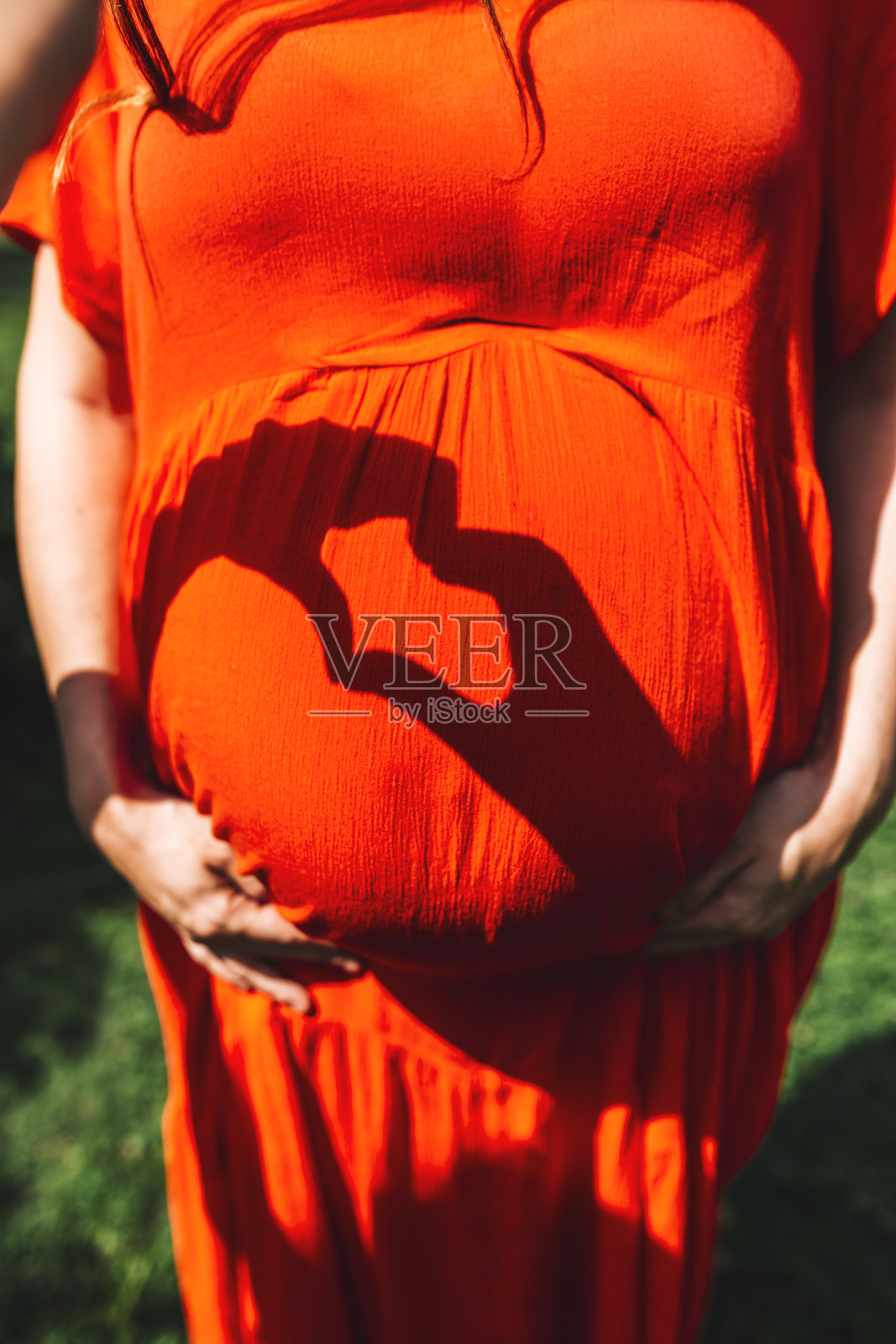 孕妇摸着大肚子在公园里散步照片摄影图片