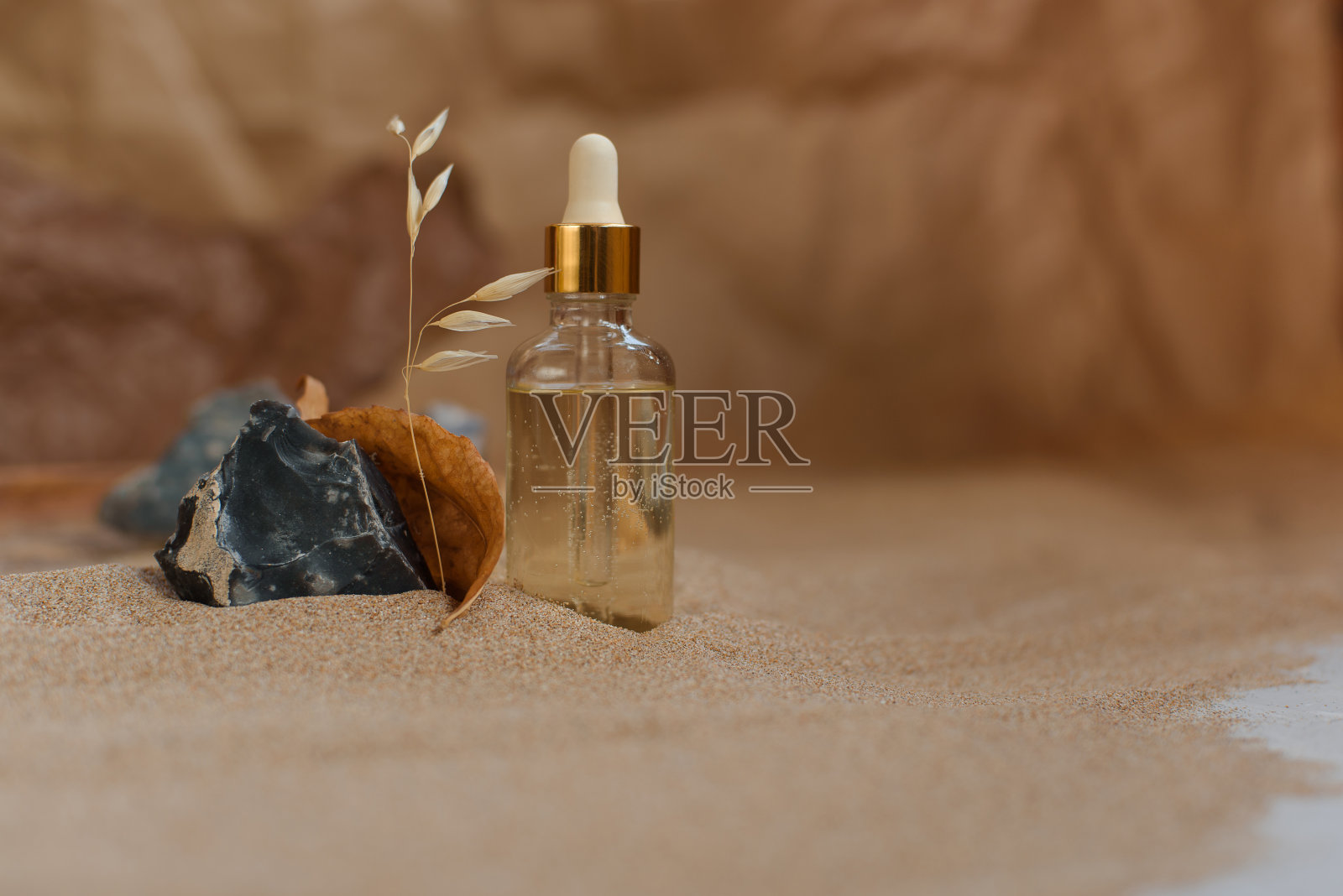 装有吸管的瓶子，装满香精、油或香水。背景砂纸和牛皮纸。照片摄影图片