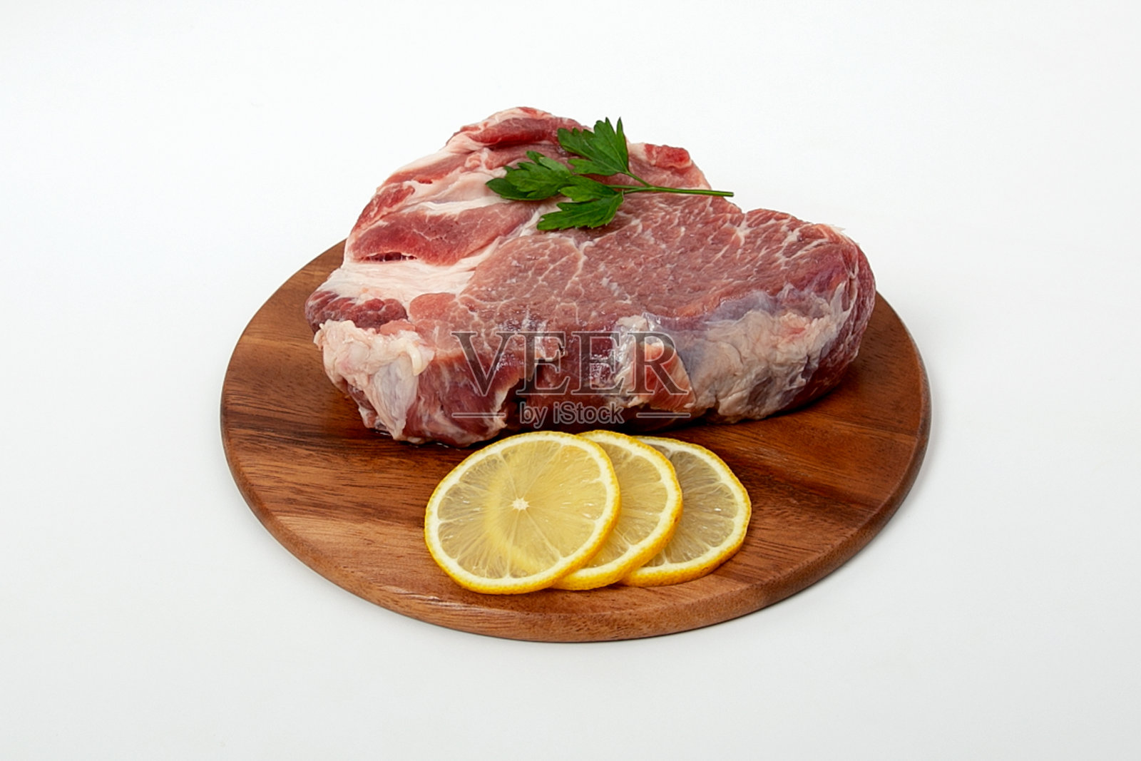 一块生肉，猪肉和柠檬放在木背上照片摄影图片