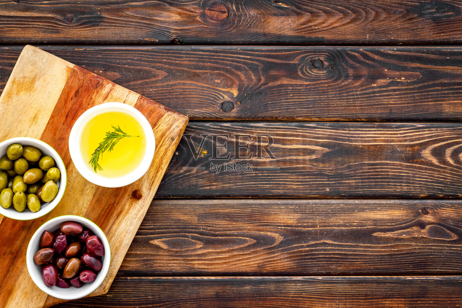 绿橄榄和黑橄榄，用碗盛橄榄油，从上至下放在砧板上照片摄影图片