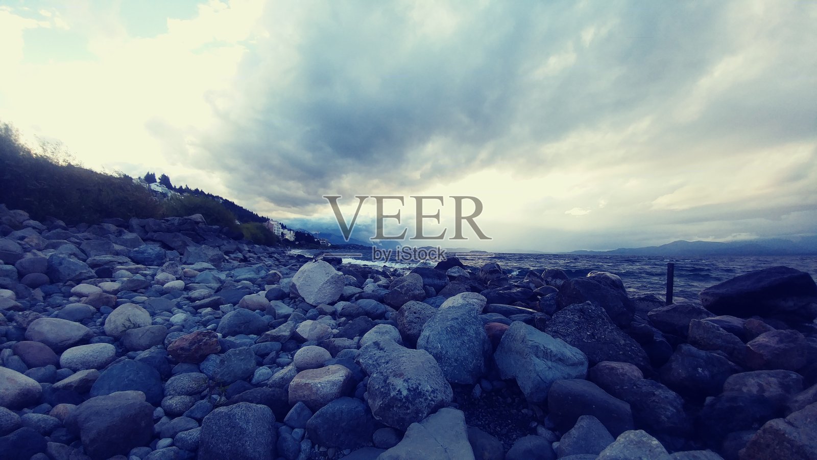 前景的岩石，灰色的石头，纳乌尔瓦皮湖在背景和多云的天空照片摄影图片