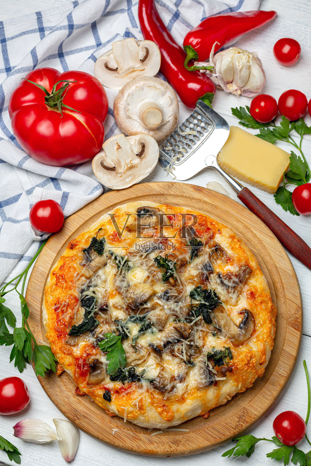 自制披萨配西红柿、菠菜和蘑菇。照片摄影图片