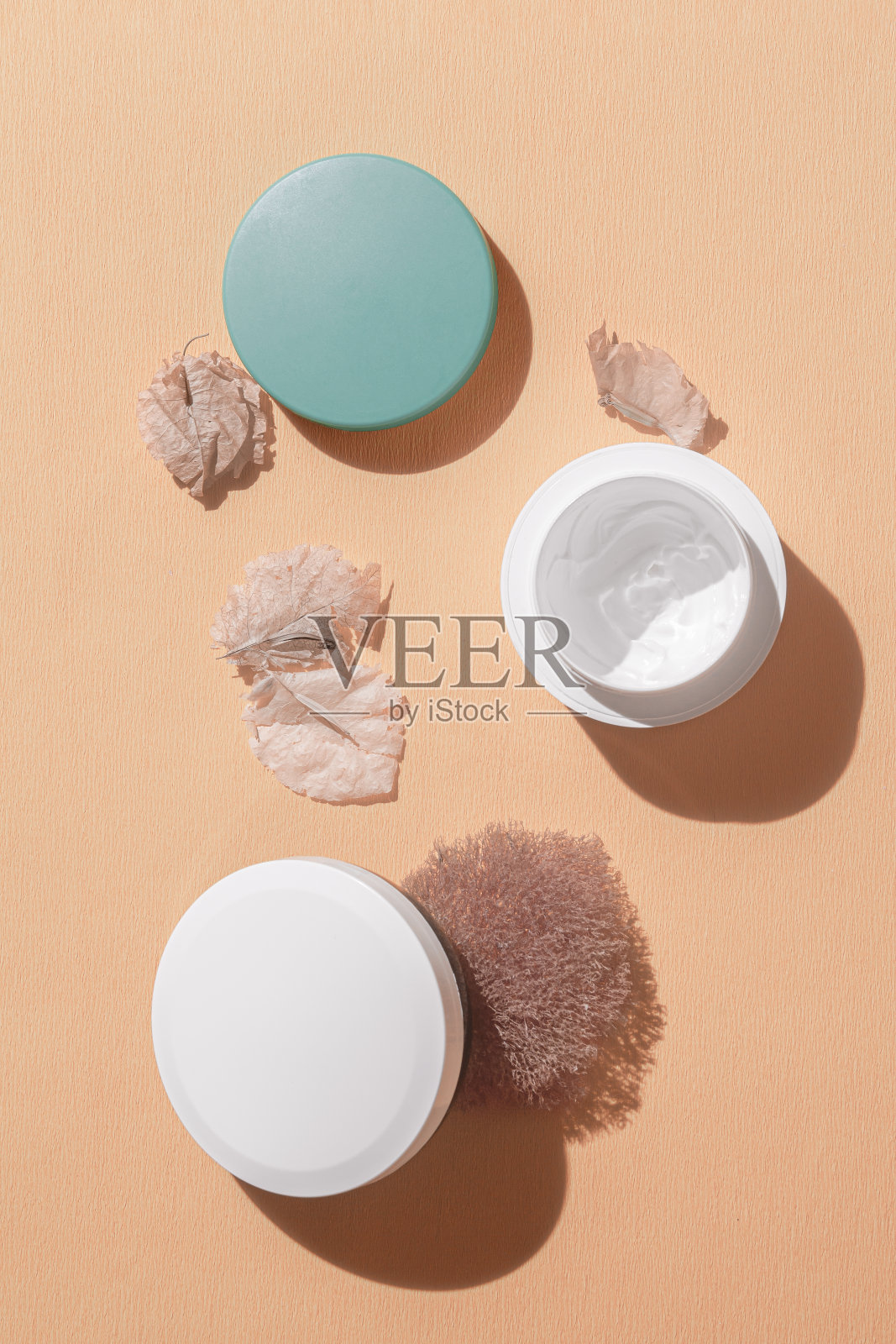 白色奶油在桃子波纹的背景与干叶，干苔藓。适合干性皮肤的霜。平的。灭克磷照片摄影图片