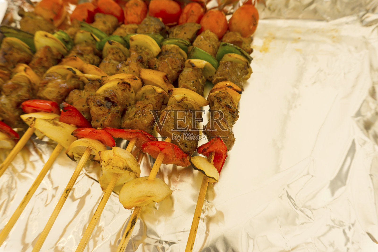 铝箔烤猪肉，一根木棒上有猪肉、红青椒、洋葱、番茄，有拷贝空间照片摄影图片