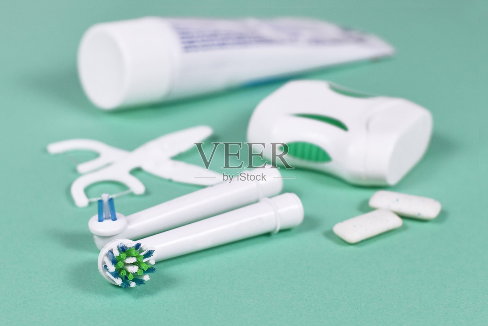 电动牙刷头与其他牙科保健设备在模糊的薄荷绿色背景照片摄影图片