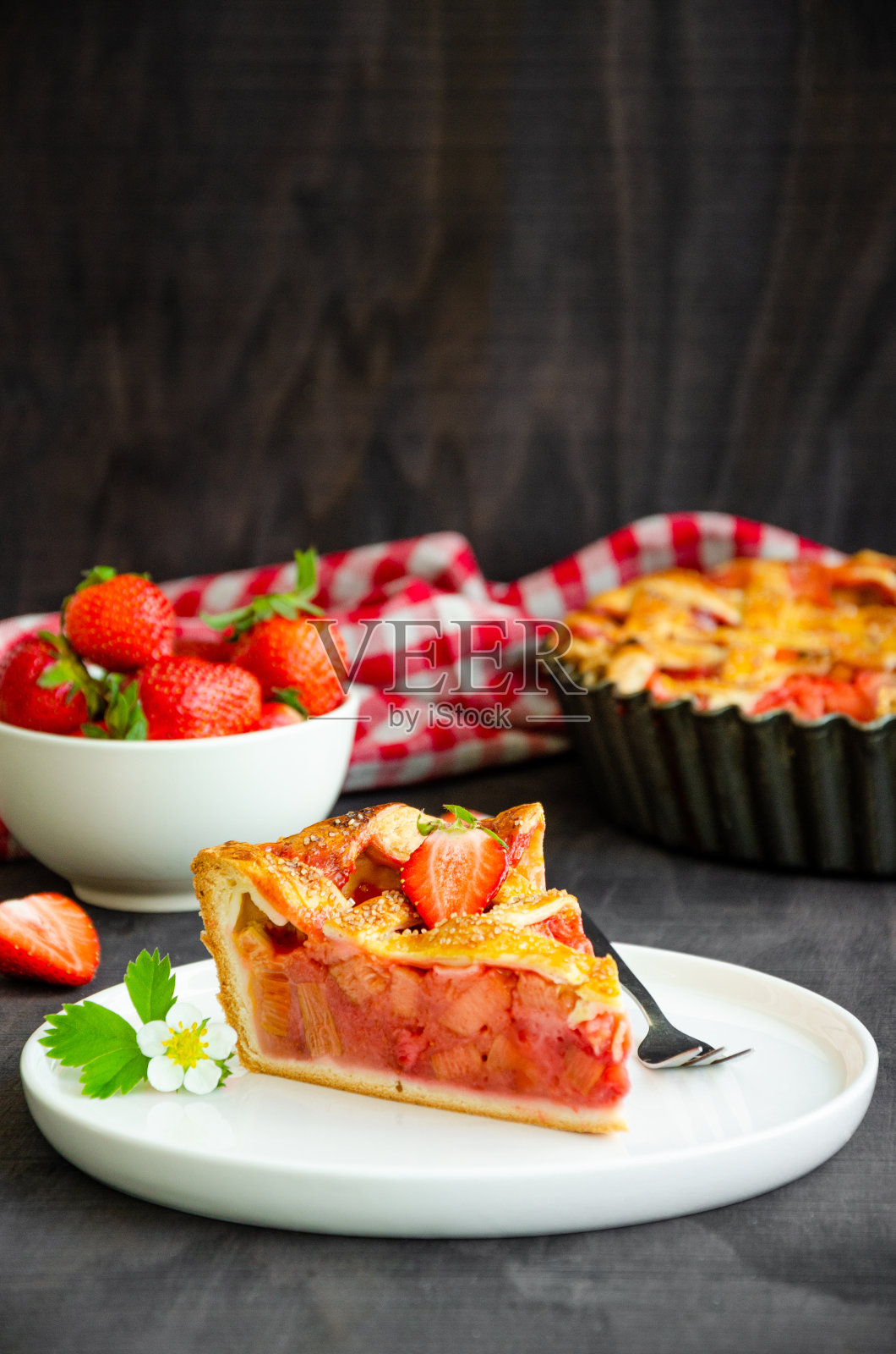 大黄和草莓派与新鲜的草莓在深色的木头背景。垂直方向，复制空间。照片摄影图片