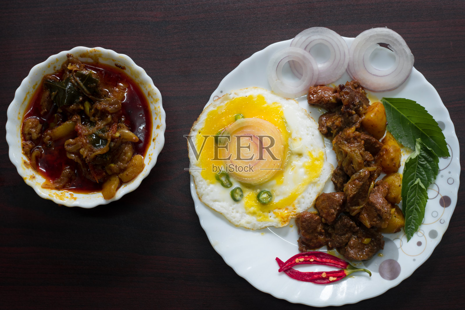 美食摄影，牛眼，鸡蛋配上辣椒和洋葱，看起来很好吃。以切菜桌、刀和汤匙作背景装饰。照片摄影图片