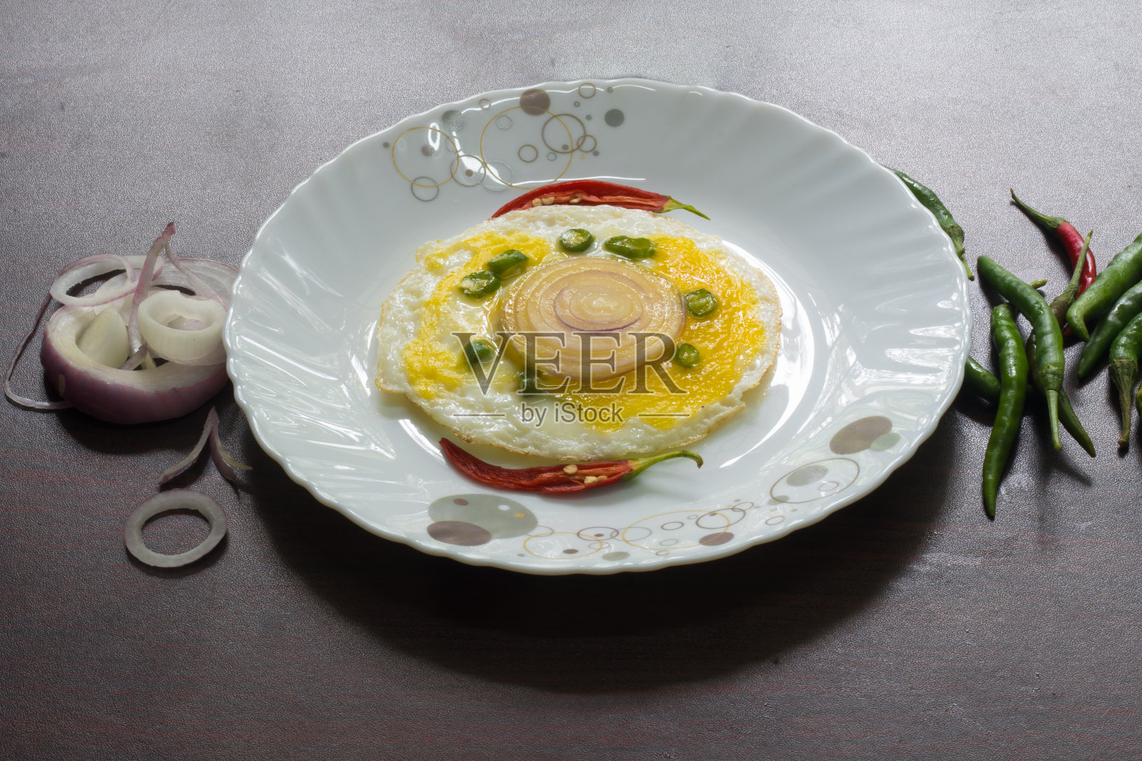 美食摄影，牛眼，鸡蛋配上辣椒和洋葱，看起来很好吃。以切菜桌、刀和汤匙作背景装饰。照片摄影图片