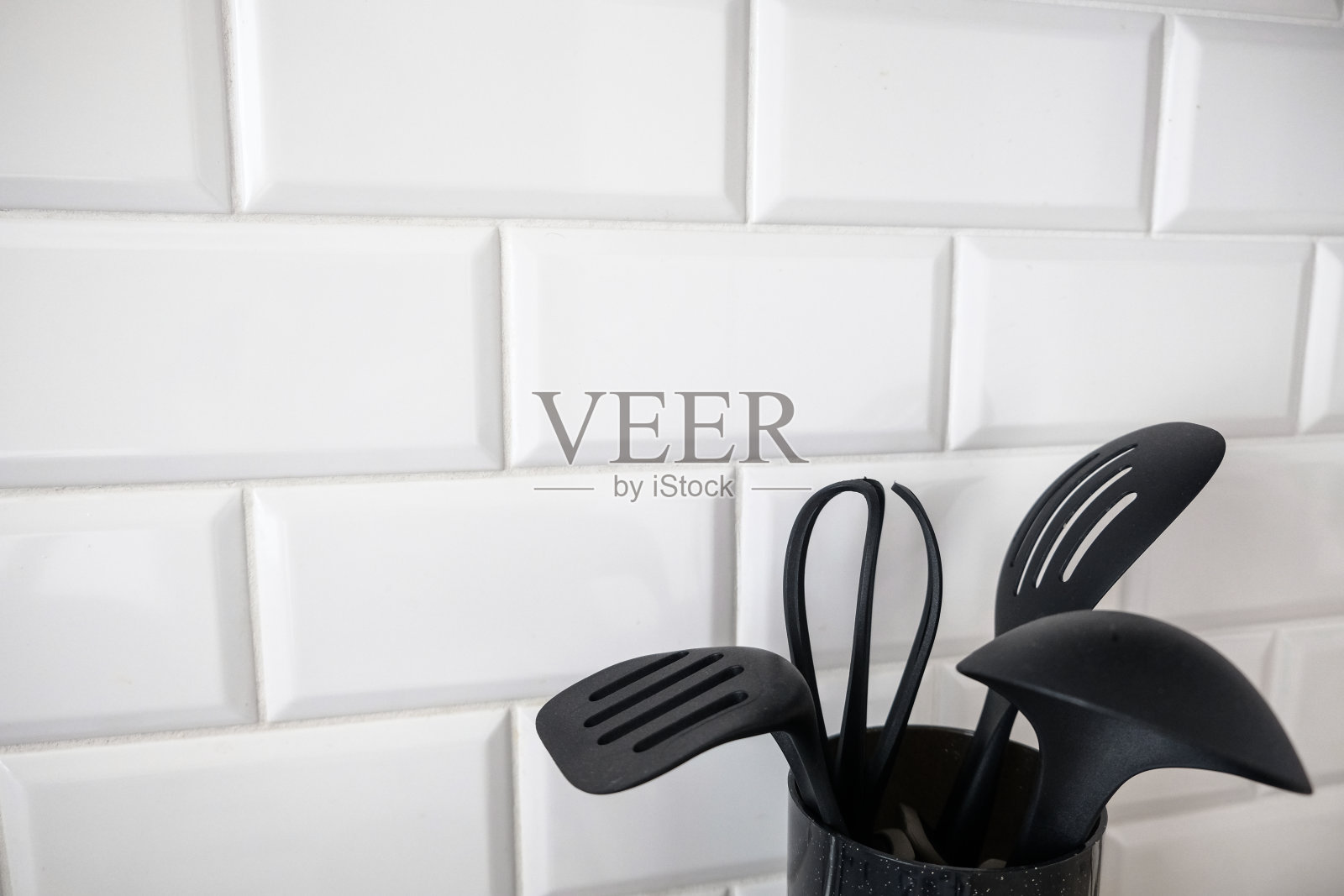 黑色的厨房用具在角落的白色瓷砖墙的背景照片摄影图片
