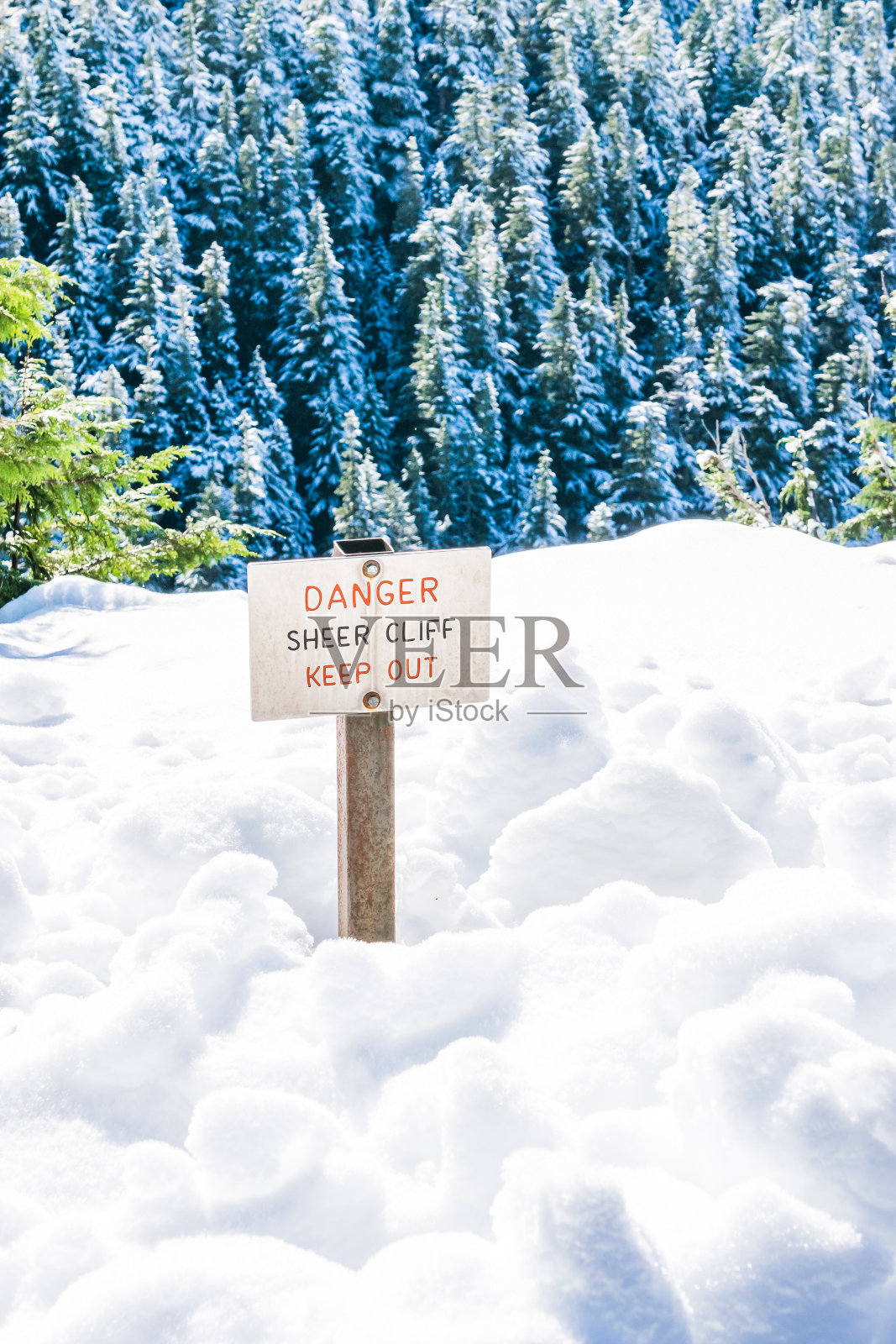 在被雪覆盖的土地边缘，有危险、陡峭的悬崖、禁止通行的标志。照片摄影图片