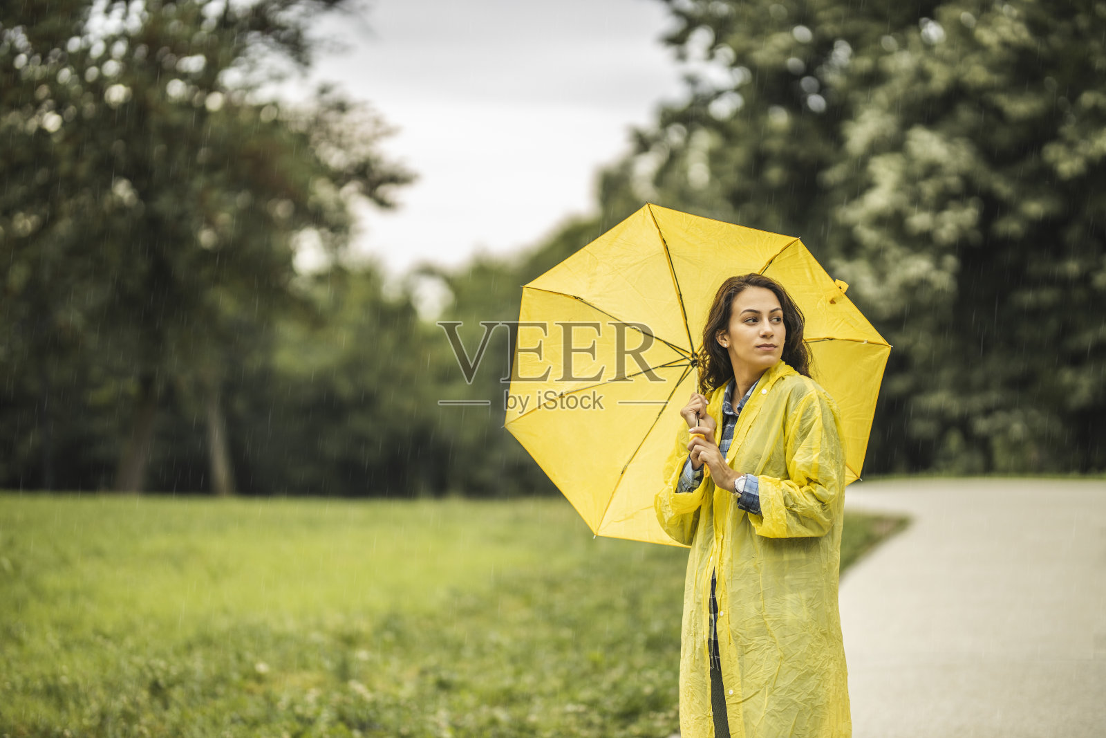 穿着雨衣，打着伞在雨中行走的女人照片摄影图片